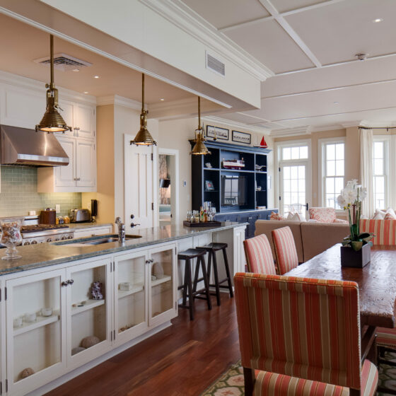 A kitchen and dining area with a living room in the background.