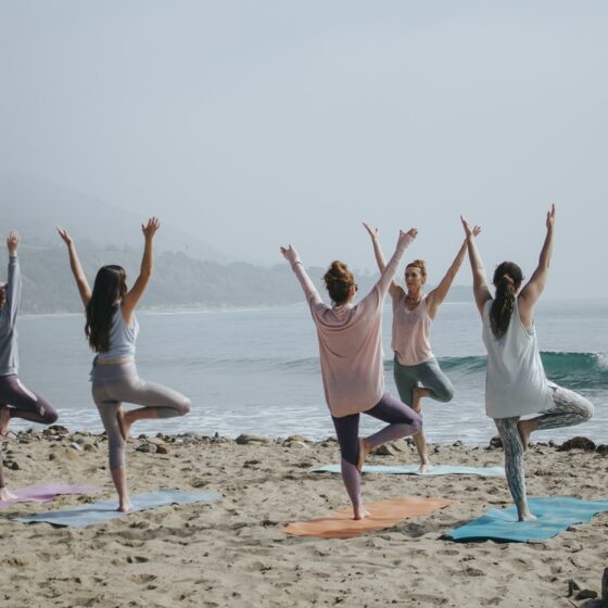 A group of people practicing yoga on a beach.