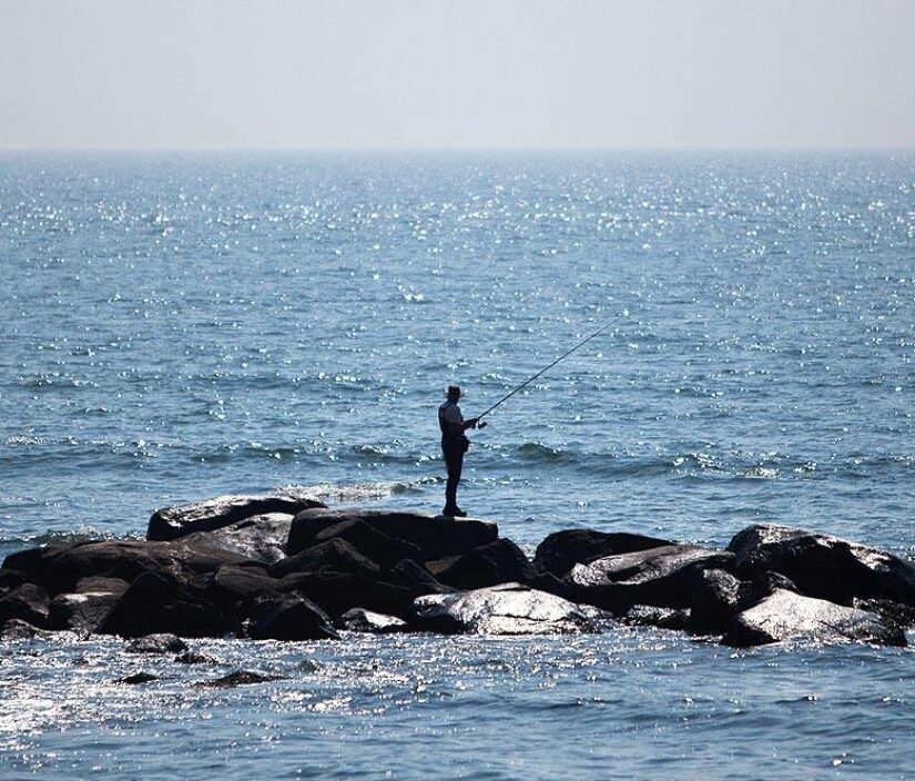A man fishing on the rocks.