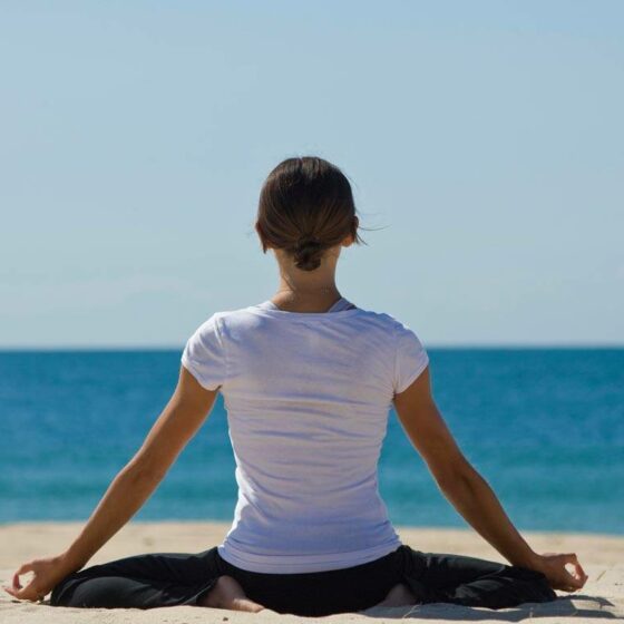 A person meditating on a beach.