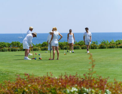 A group of people play croquet.