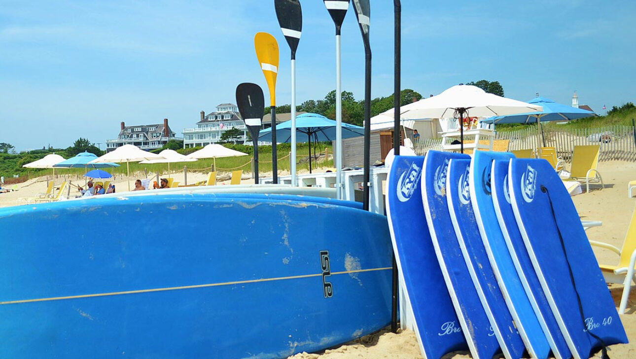 A surf board and a stack of paddle boards.