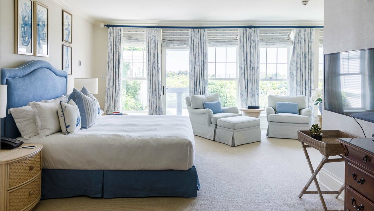 Blue Skies Suite bedroom with large windows and two seats.