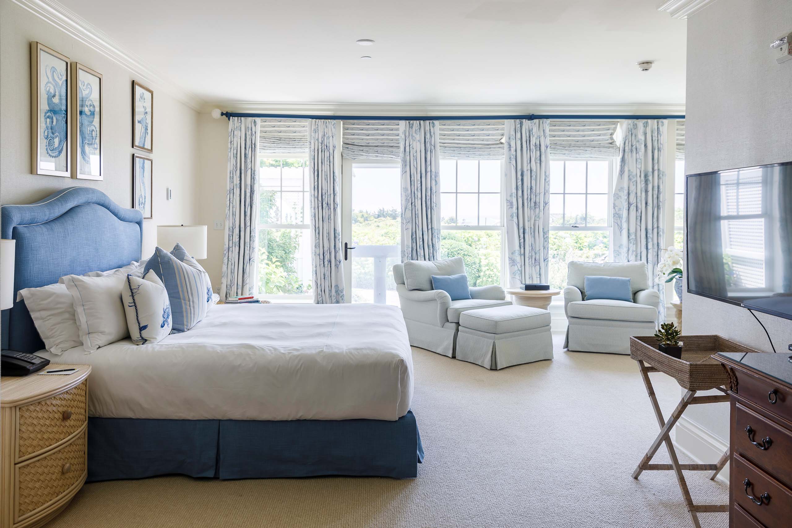 Blue Skies Suite bedroom with large windows and two seats.