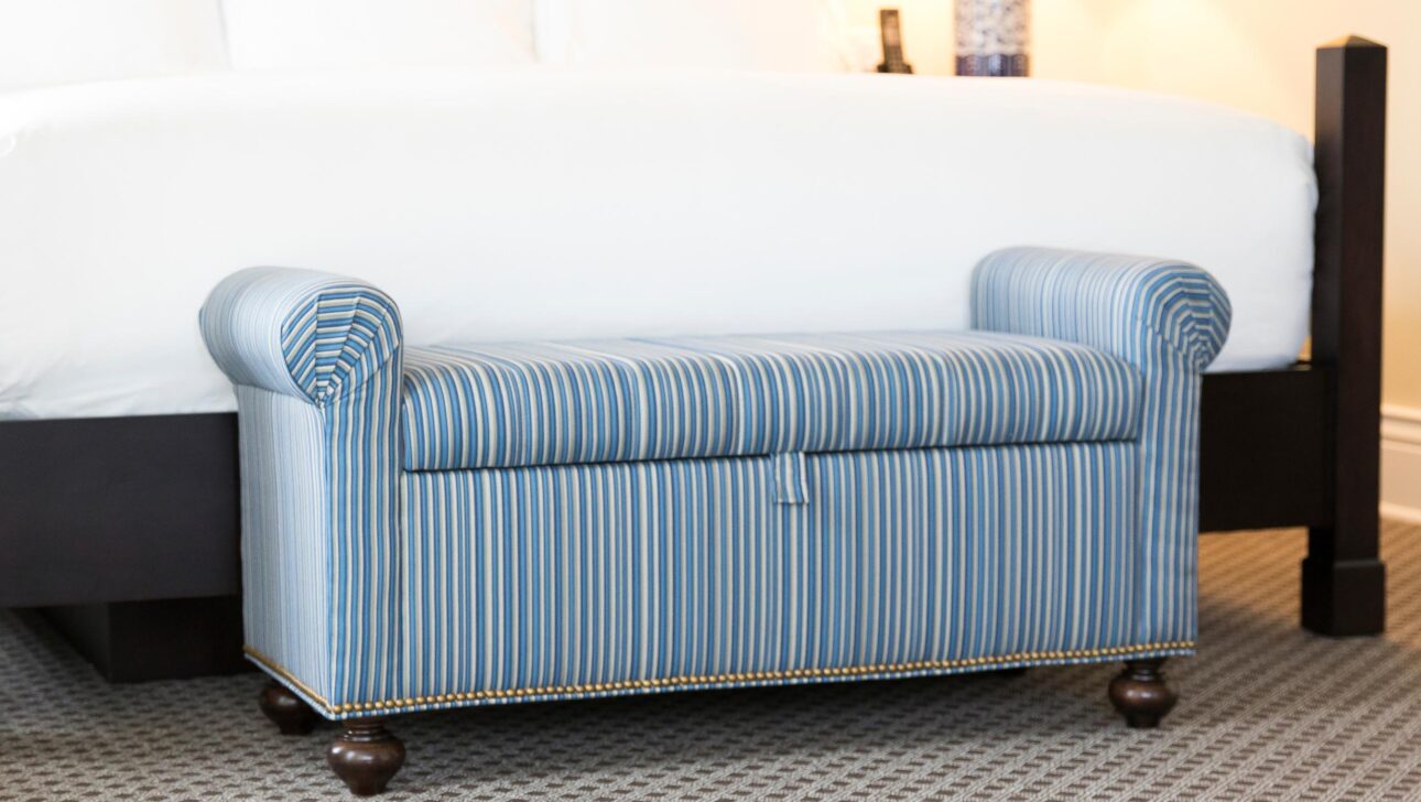 A blue footrest at the end of a bed.