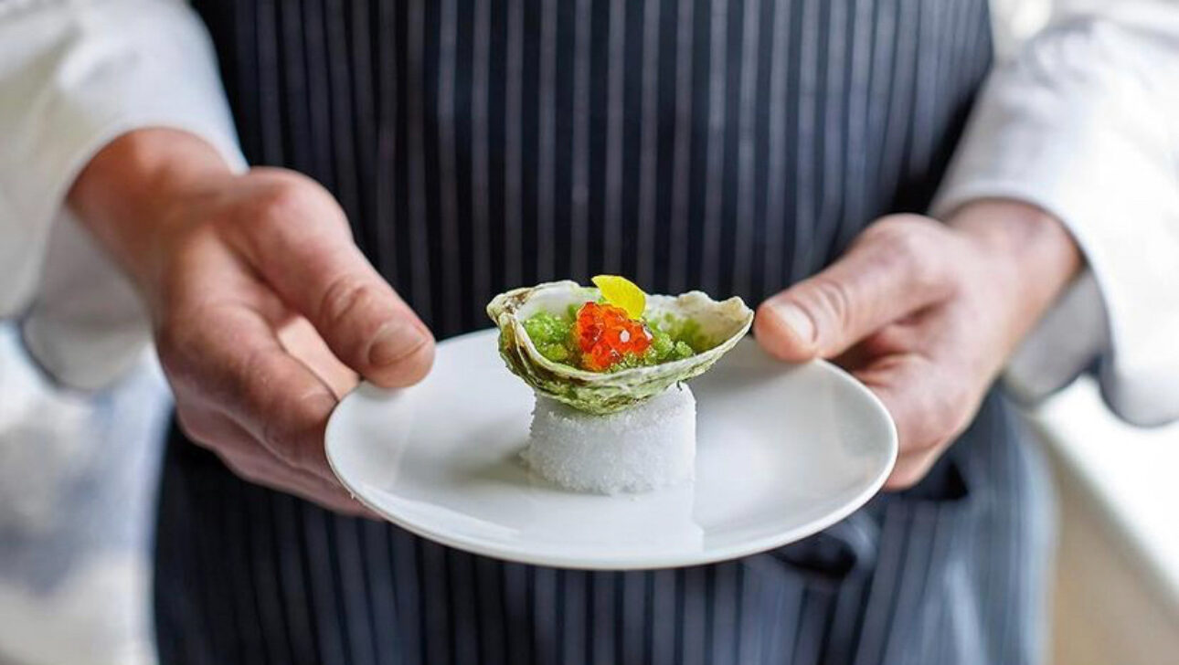 A chef holding a dish at COAST restaurant.