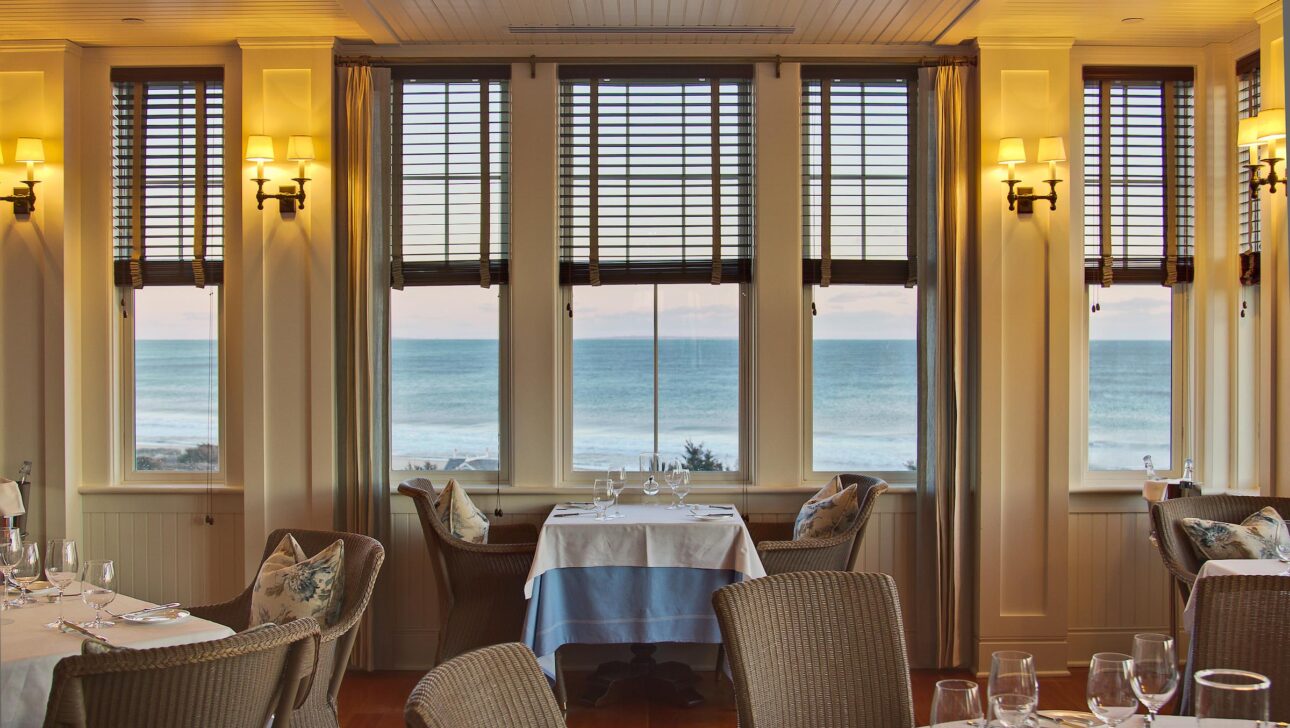Coast restaurant dining area with windows showing an ocean view.