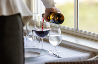 A server pouring a glass of red wine.