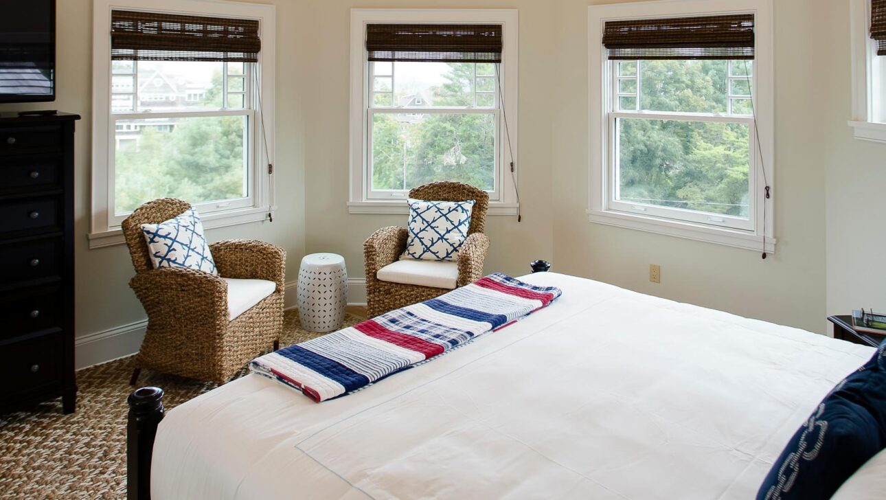 A bedroom in Echo Lodge with two chairs and several windows.