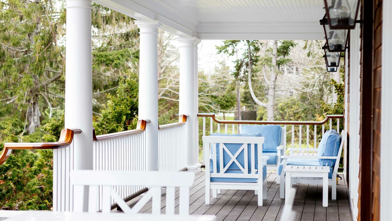 A veranda with three blue lounge chairs.