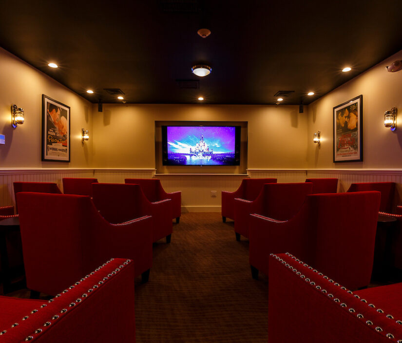 A screening room with red chairs.