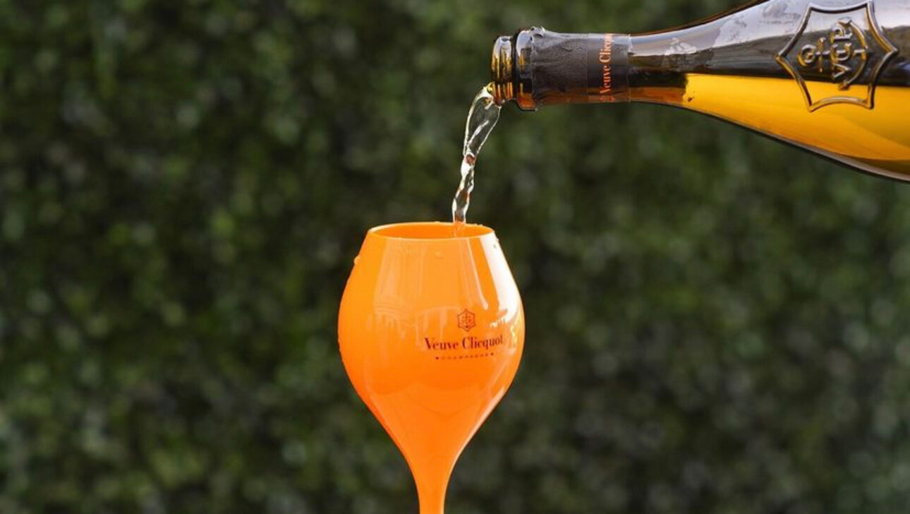 Champagne being poured into an orange glass.
