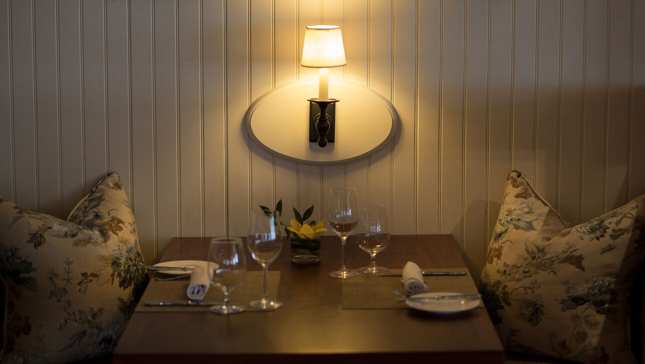 A dimly lit dining table set for two.