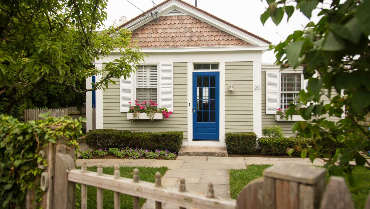 The outside of a cottage with a blue door.