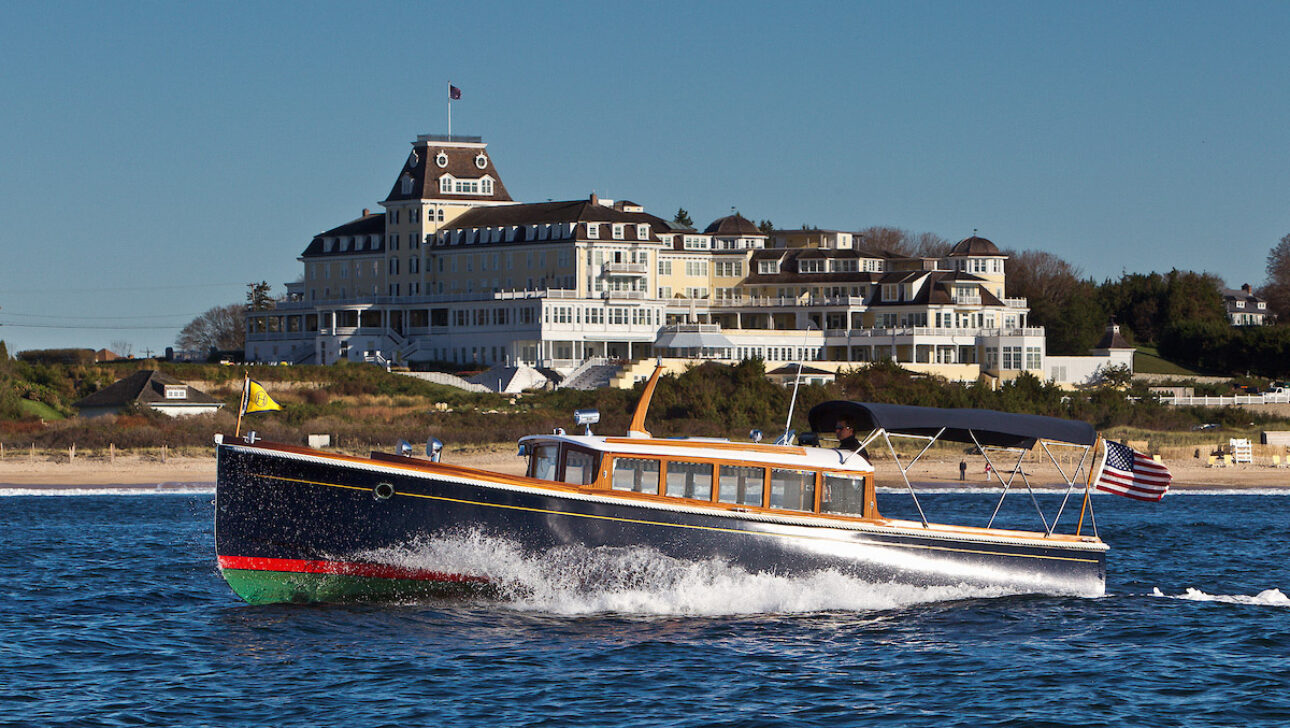 A yacht on the water with Ocean House Hotel in the background.