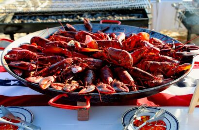 A large pan filled with cooked lobsters is placed on an American flag tablecloth.